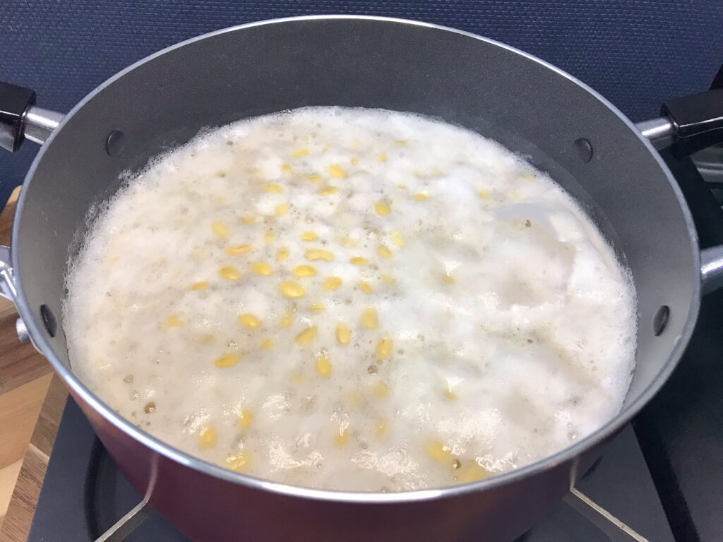 水で戻した大豆を鍋で茹でながらアク抜き